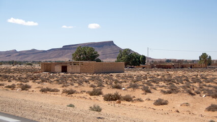 Collection of houses along the highway near Kebili, Tunisia, with the Atlas Mountains in the...