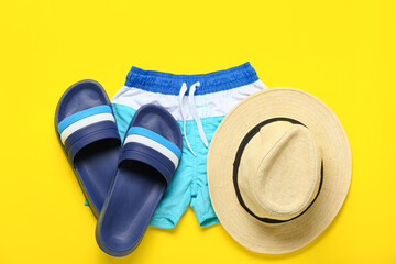 Flip-flops with shorts and hat on yellow background