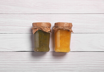 Jars with preserved fruit jams on white wooden table, flat lay