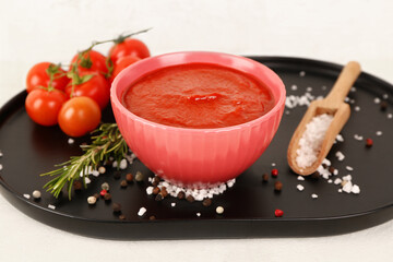Bowl with tasty tomato paste on light background