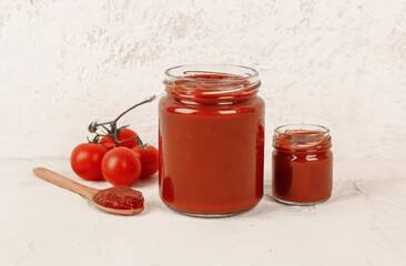 Jars with tasty tomato paste on light background