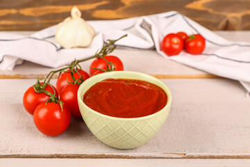 Bowl with tasty tomato paste and fresh vegetables on table
