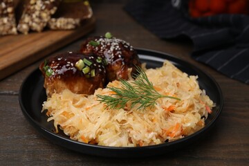 Plate with sauerkraut and chicken on wooden table, closeup