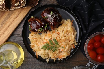 Plate with sauerkraut, chicken and products on wooden table, flat lay