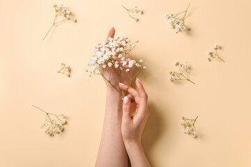 Obraz na płótnie Canvas Woman with gypsophila flowers on beige background. Hand care concept