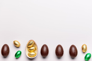 Sweet chocolate Easter eggs and candies on light background
