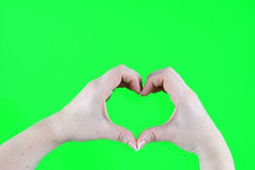 Fototapeta premium female hand heart shape with shadow against green background. Valentines day. creative adorable decoration idea with copyspace. High quality photo