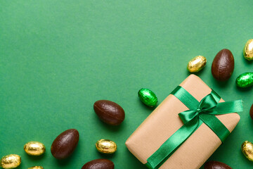 Chocolate Easter eggs and gift box on green background