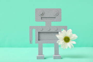 Decorative plaster robot with chamomile flower on turquoise background