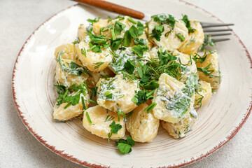 Plate of tasty Potato Salad with greens on light background