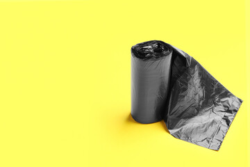 Black roll of garbage bags on yellow background