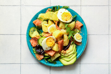 Plate of tasty potato salad with eggs and avocado on light background, top view