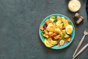 Plate of tasty potato salad with eggs and avocado on dark background, top view