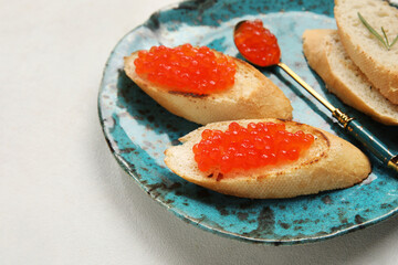 Tasty bruschettas with red caviar on white background