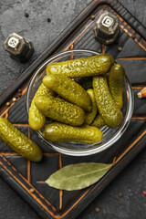 Bowl with tasty fermented cucumbers on dark grunge background