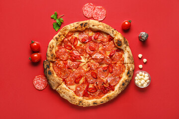 Delicious pepperoni pizza and ingredients on red background