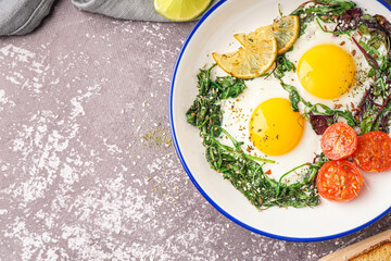 Plate with tasty fried eggs and salad on grey background