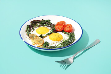 Plate with tasty fried eggs and salad on blue background