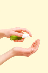 Woman applying sanitizer on beige background