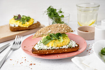 Plate with tasty scrambled eggs sandwich on light background