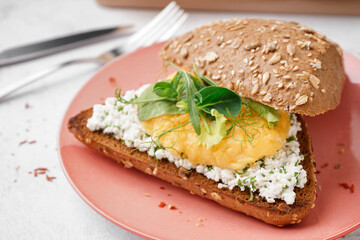Plate with tasty scrambled eggs sandwich on light background