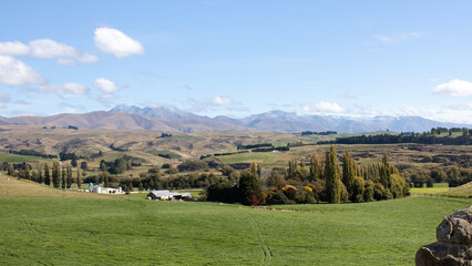 Fototapeta na wymiar Landscape of fields, mountains and blue sky in autumn on the south island of New Zealand. 