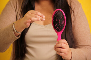 Latin adult woman with very long straight hair suffers from hair loss looking at the brush how many...