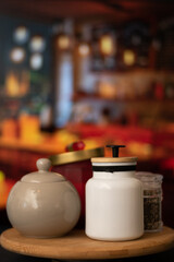 Vertical view of Mugs of sugar and salt containers style vintage over a table in night restaurant with selective focus and bokeh background