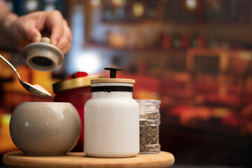 Hand taking sugar from Mugs of sugar and containers over a table in night restaurant