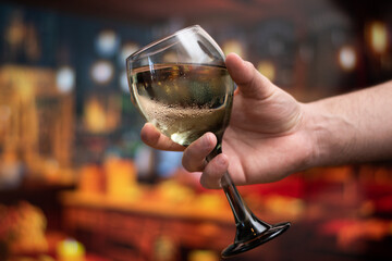 Close up of hand holding a cup of wine with copy space and bokeh in background