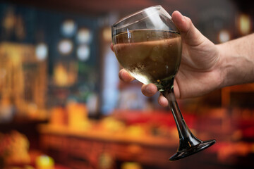 Close up of hand holding a cup of wine with copy space and bokeh in background