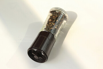 Glass black pepper corns shaker isolated on white background