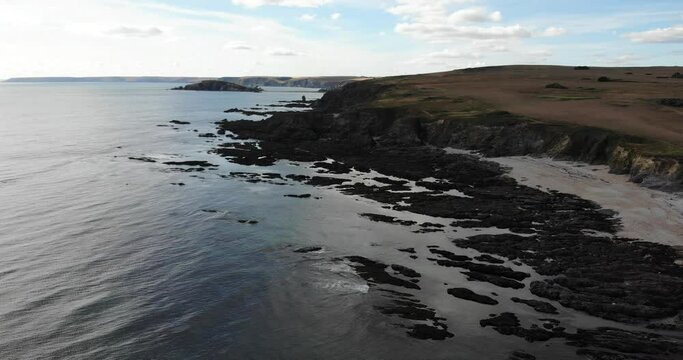 Drone descends over coastline and rocky cliffside shore, Thurlestone, South Devon England