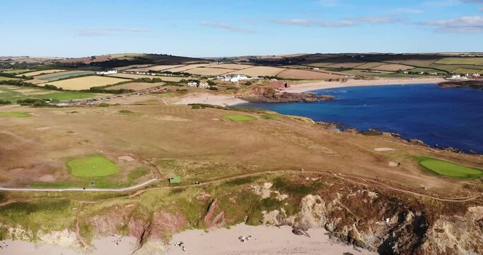 Aerial pan of Thurlestone Golf Course and cliffs. From blue ocean to land.