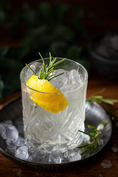 A white negroni bianco cocktail with lemon and rosemary herb garnish.