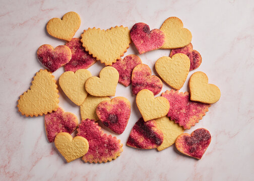 Stamped Heart Cut-Out Cookies with Pink Sugar on a Pink Marble Background