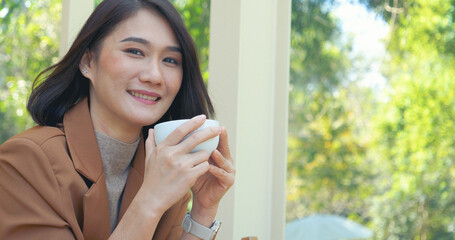 Woman holding coffee cup relaxing after work at office warm taste in cafe. Close up hands of woman sitting office desk holding sweet coffee cup relax and enjoy with happy time. Hot coffee mug in hand