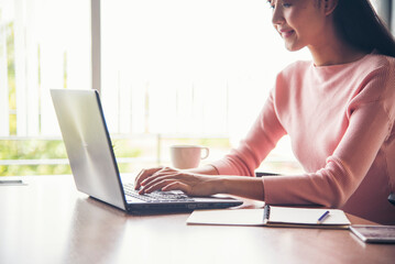 Woman working from home on laptop online meeting in home office. Entrepreneur asian business woman using notebook laptop sit on sofa technology new normal lifestyle. Happy woman typing keyboard laptop