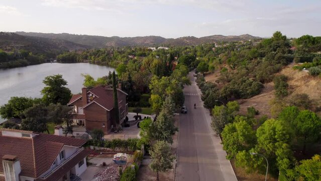 Aerial dolly out revealing a motorist passing through a residential road of villas with his hands raised