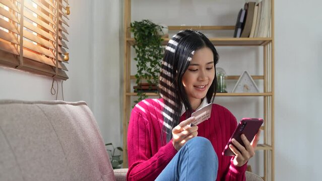 Happy woman holding bank card, entering cvv code or payment information in mobile internet shopping application