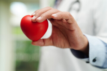 Asian woman doctor holding red heart for health in hospital.