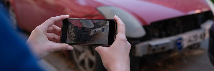 Female insurance broker making photos of car after accident on modern smartphone