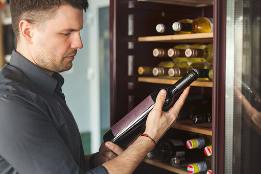 Man chooses bottle of aged vintage wine in winehouse.