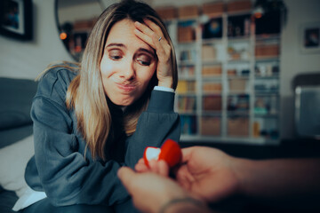 Unhappy Girlfriend Receiving an Unwanted Engagement Proposal. Stressed woman refusing a gift from a suitor 
