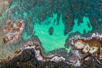 Aerial view of coral reef and rocky shoreline in tropical ocean 