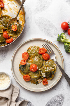 Spinach and broccoli vegan ravioli with cherry tomatoes on a white background