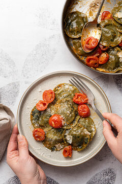 Spinach and broccoli vegan ravioli with cherry tomatoes on a white background