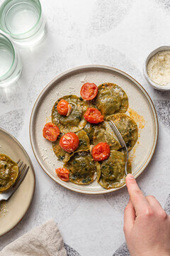 Spinach and broccoli vegan ravioli with cherry tomatoes on a white background