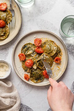 Spinach and broccoli vegan ravioli with cherry tomatoes on a white background