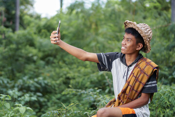 A man in a straw hat takes a selfie with a phone